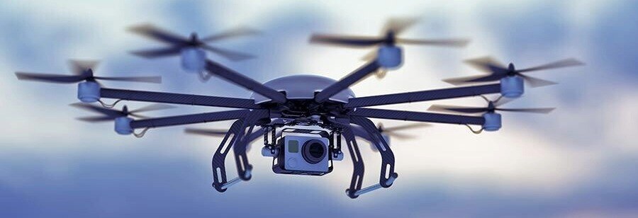 A surveillance drone with multiple rotors and a mounted camera hovering against a cloudy sky, representing the growing threat of unauthorized drone activity and security challenges in 2025.